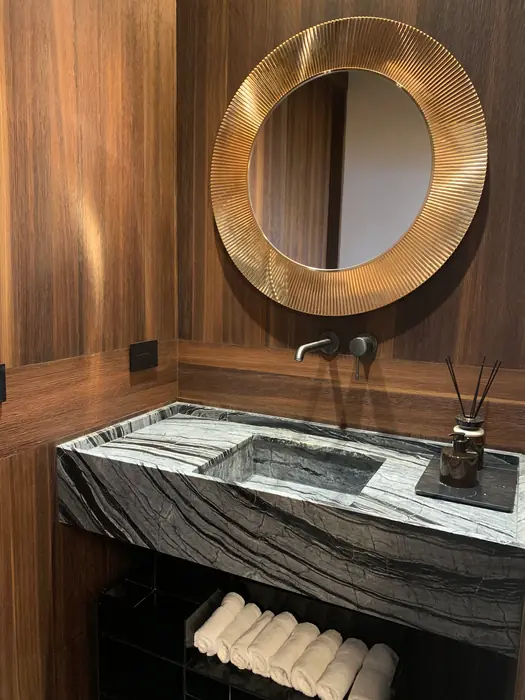 Baño de visitas con lavabo de piedra y espejo dorado sobre nogal, Casa Lomas